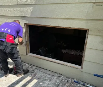 Worker installing a window in the exterior wall of a house